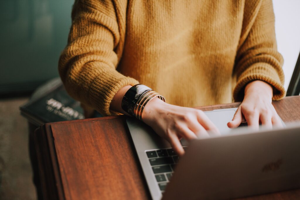 person's hands typing on a laptop