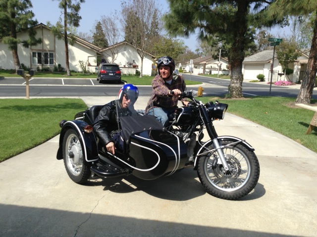 Charles sits in the sidecar of a motorbike.