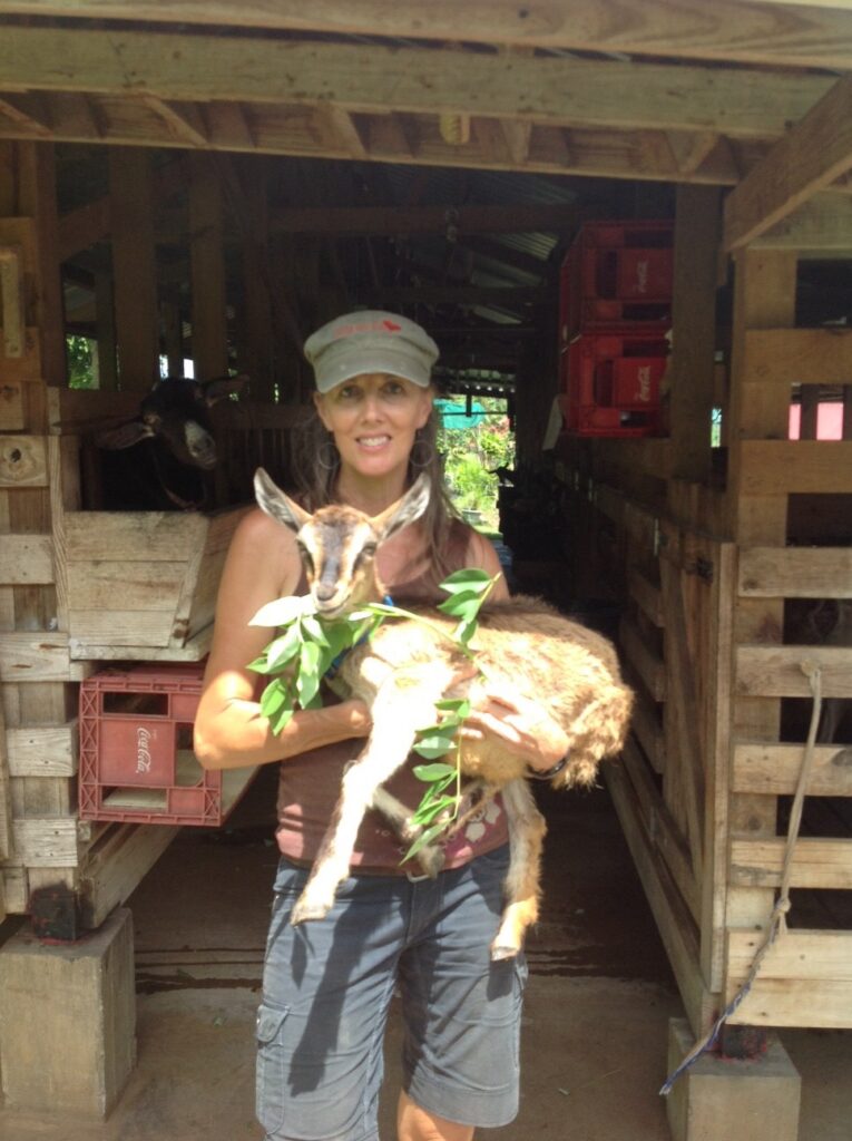 Christine holds a goat in her arms.