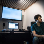 student at desk with multiple screens