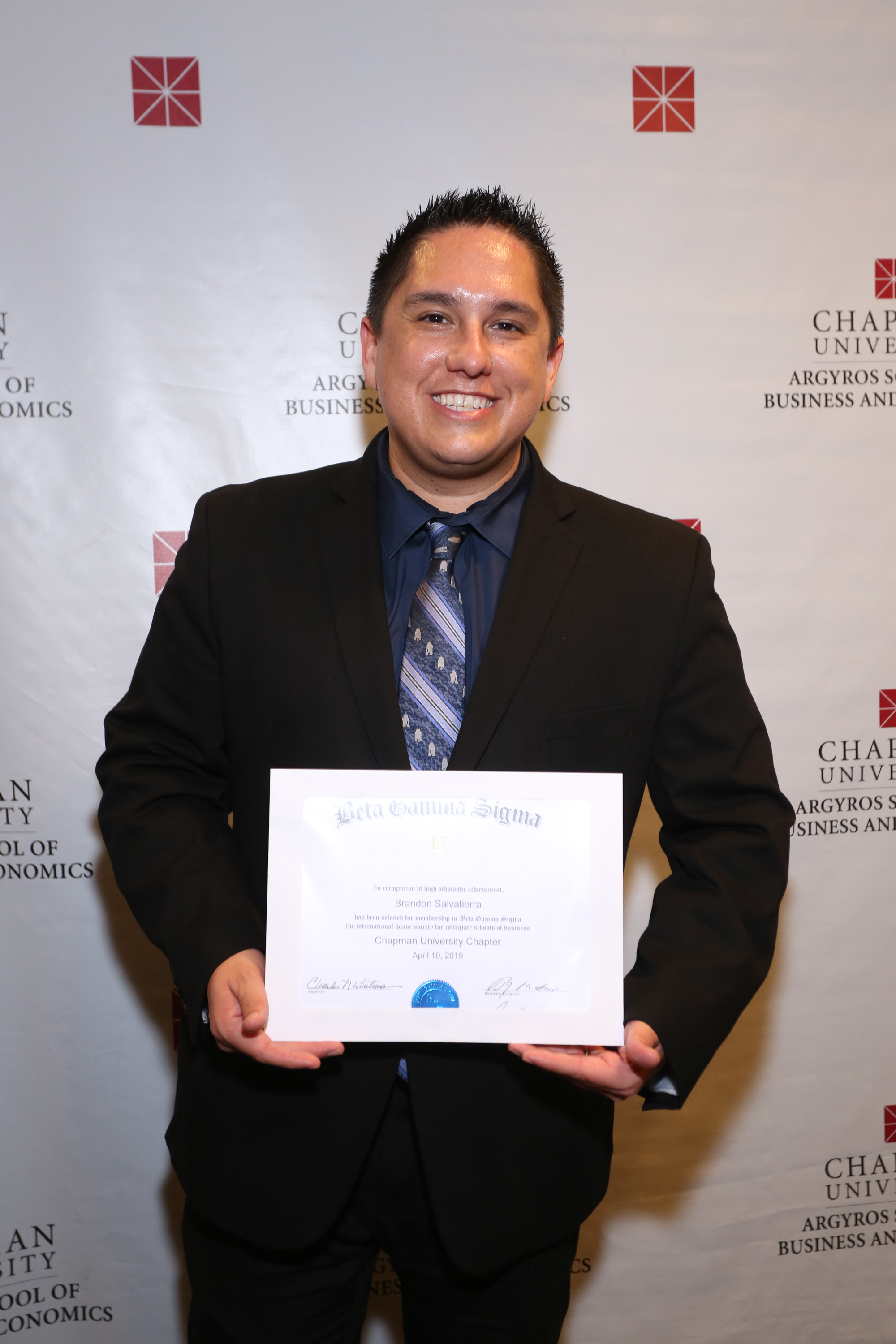 Brandon Salvatierra smiling holding his Beta Gamma Sigma Certificate