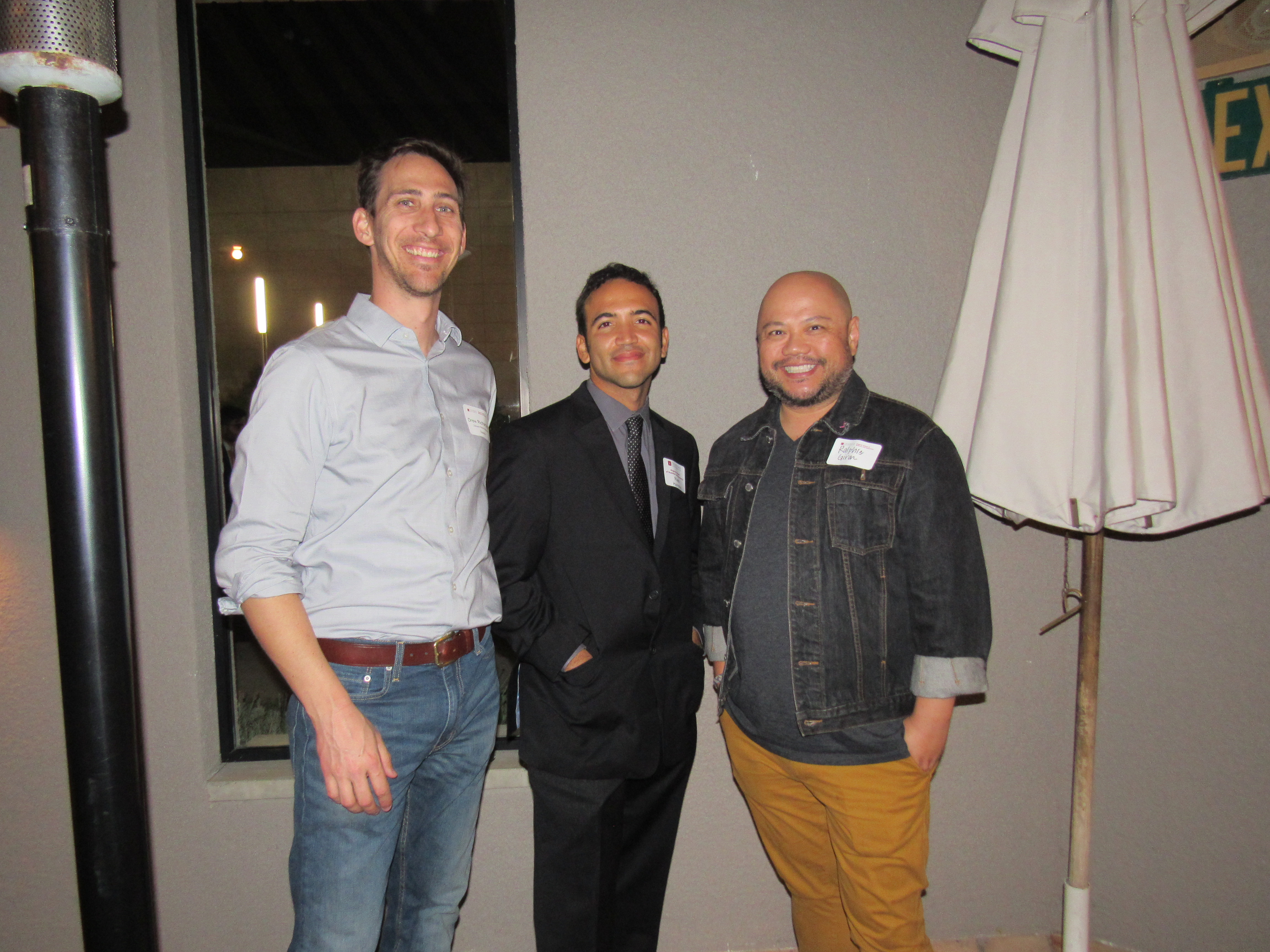 Three men smiling and standing together