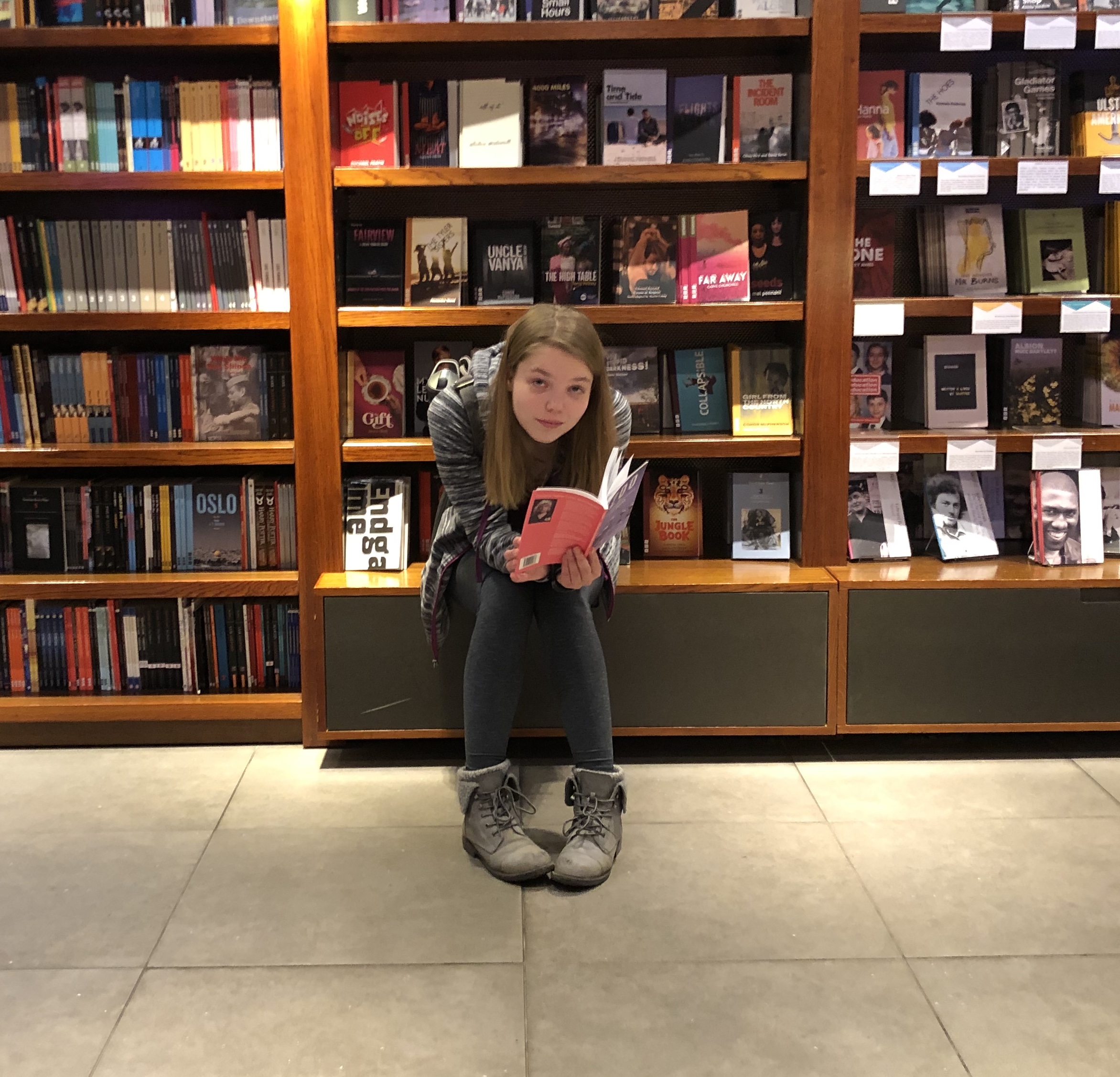 Student reading a book in front of book shelves
