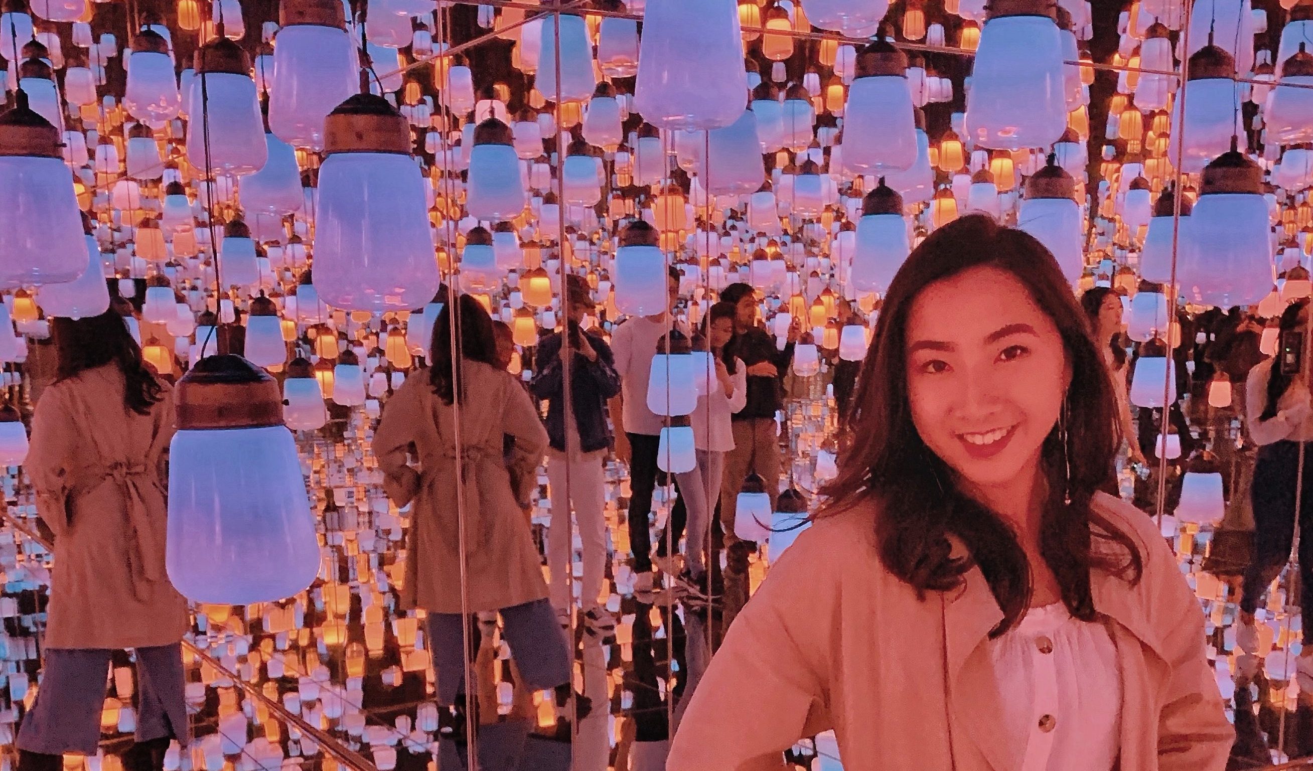 Lisa in an art musuem room filled with light bulbs hanging down from the cieling.