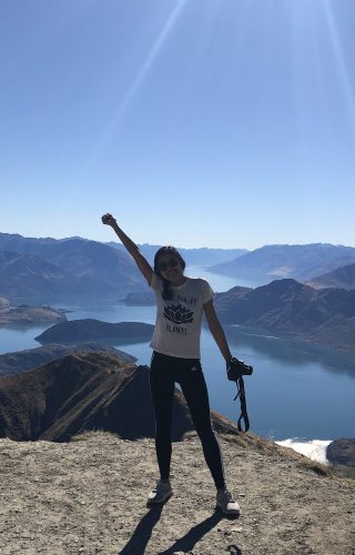 Laurel atop Roys Peak, a mountain with a lake behind it with several small islands througout.