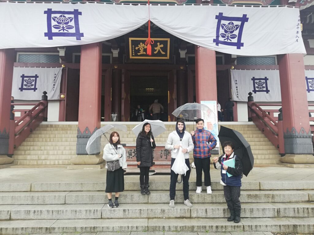Students with umbrellas on steps in front of Japan temple