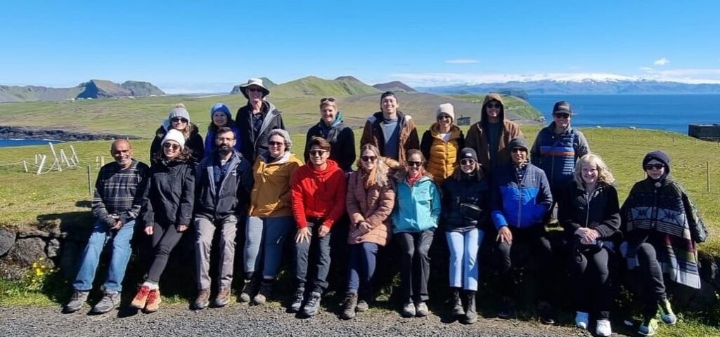 Students with green hills and ocean scenic background in Iceland