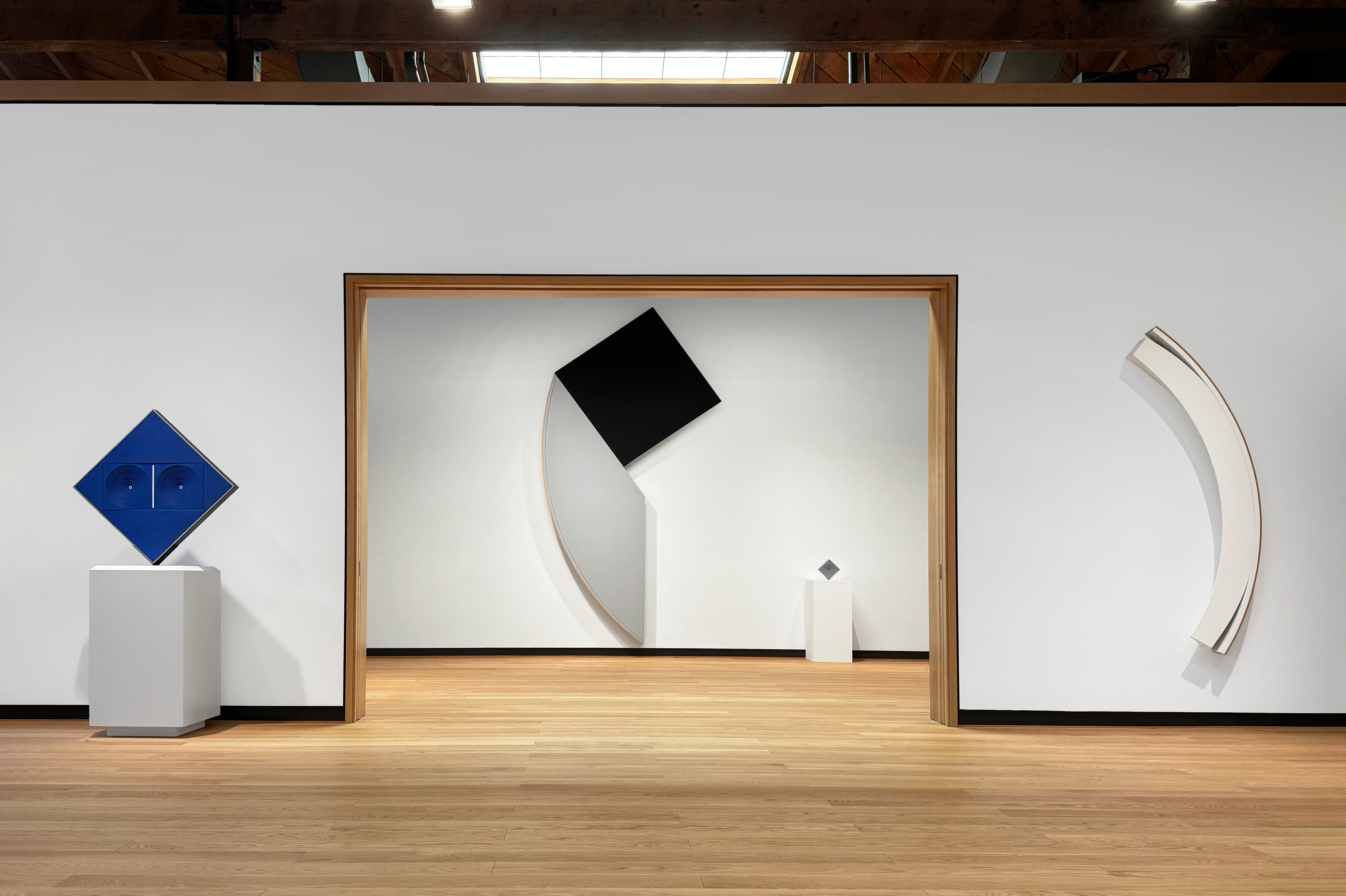 Image of contemporary art exhibition featuring geometric works painting in mostly primary colors.