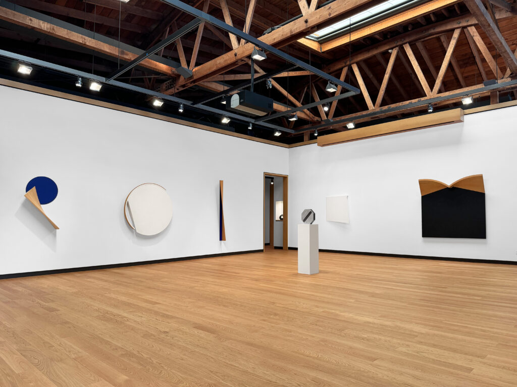 Image of contemporary art exhibition featuring geometric works painting in mostly primary colors.