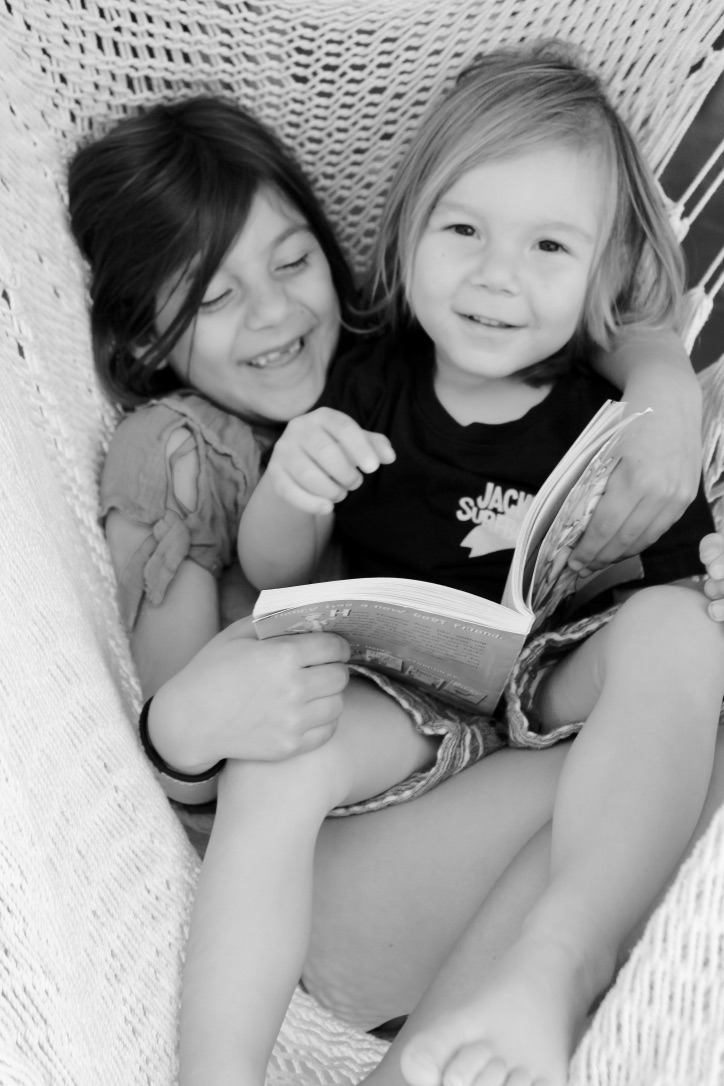 Reading her Language Arts book to her brother
