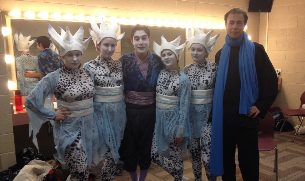 Students pose backstage in costumes at festival.