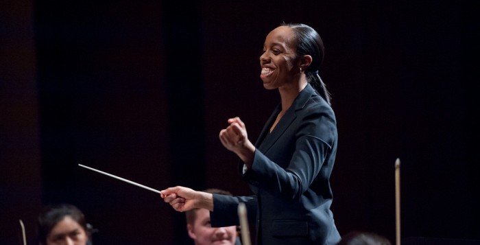 Conductor smiling and holding her baton.