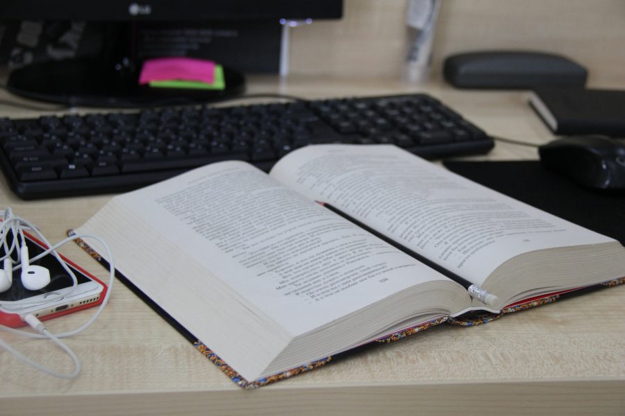 open book on table with headphones and computer keyboard