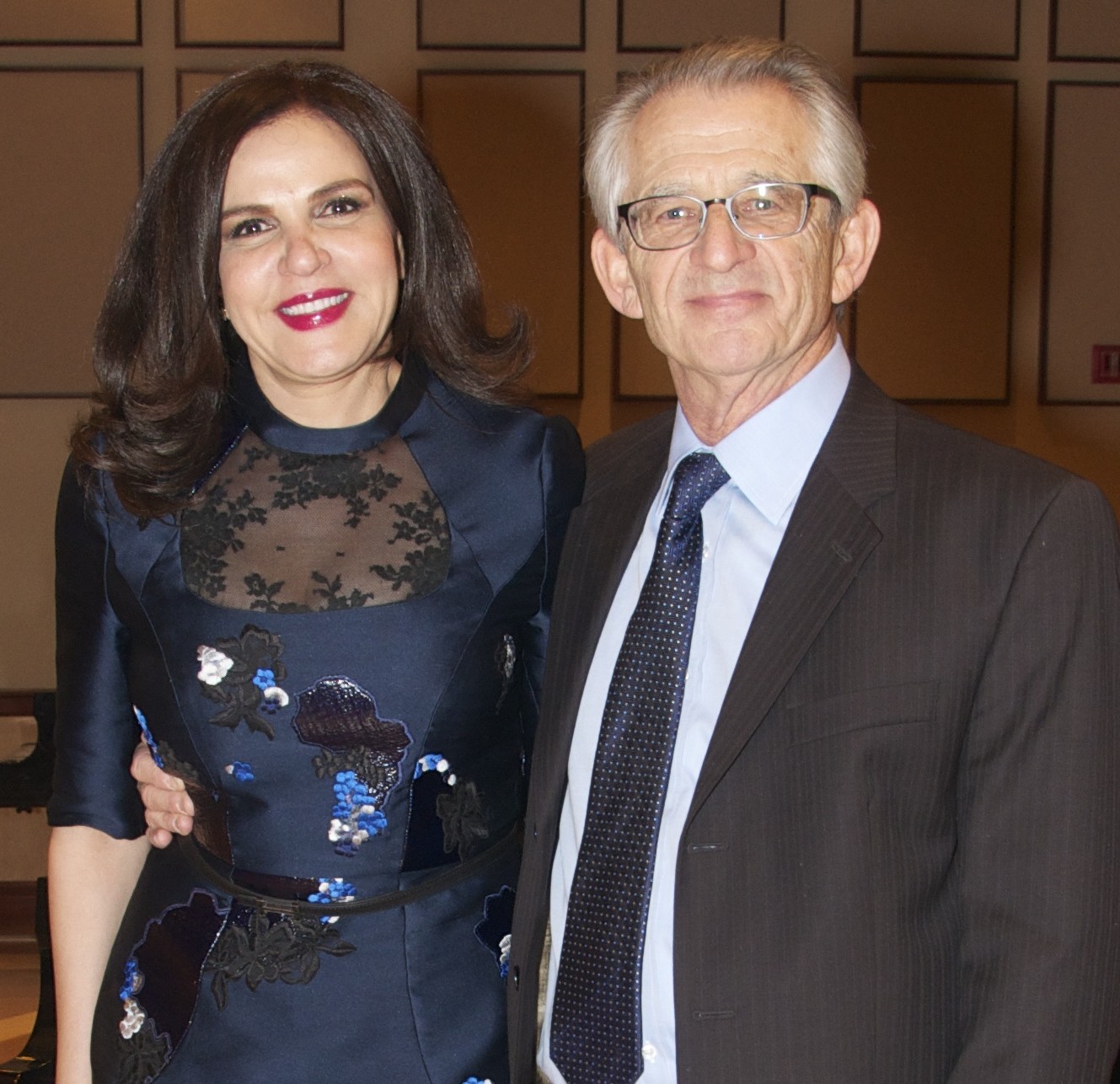 Smiling woman with long dark hair next to smile man with gray hair and glasses