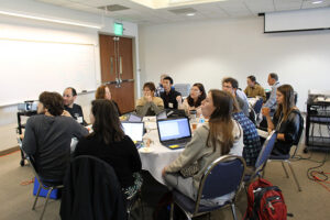 Students on their computers, discussing things at the Big Data event at Chapman