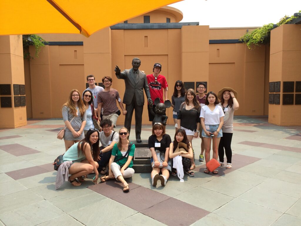 Image of Chapman Students posing with the Walt Disney statue outside of Disney Studios