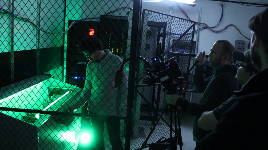 green lit storage room with man inside and cameras pointed at him