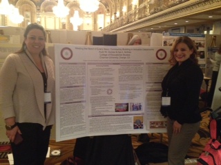 Two women standing next to presentation board.