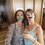 Two women posing with fake mustaches.
