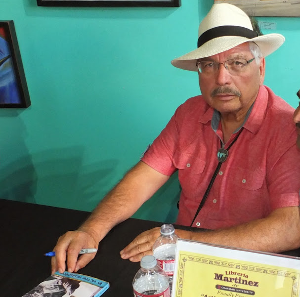 Man with marker sits at table for book signing.