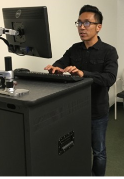 Man stands at a computer, typing.
