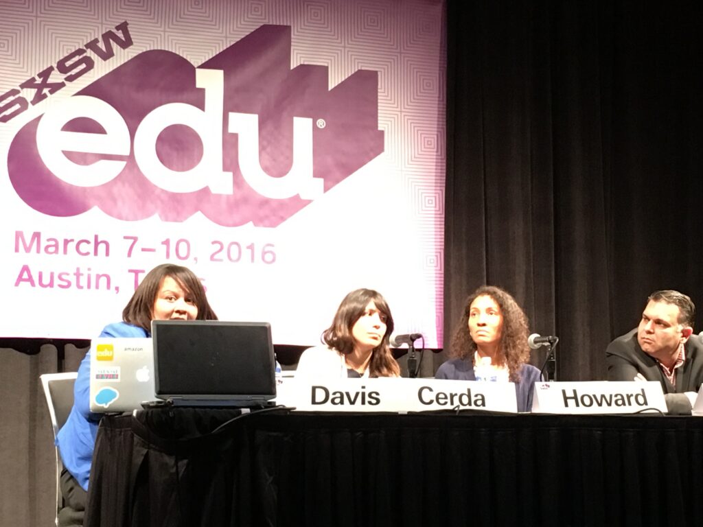 Four people sit at a table with a SXSW edu sign behind them.