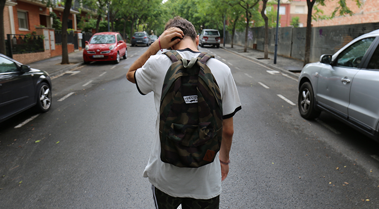 teenage boy walking down a street with back to the camera