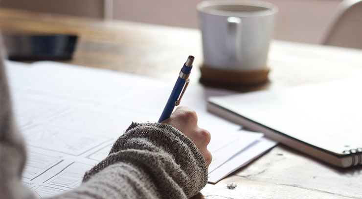 Hand writing on test papers with a coffee mug on the desk