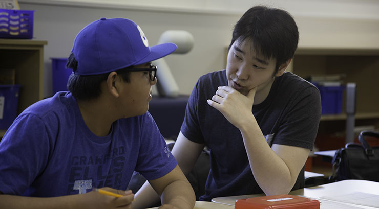 Male adult talking with male adolescent in a classroom setting