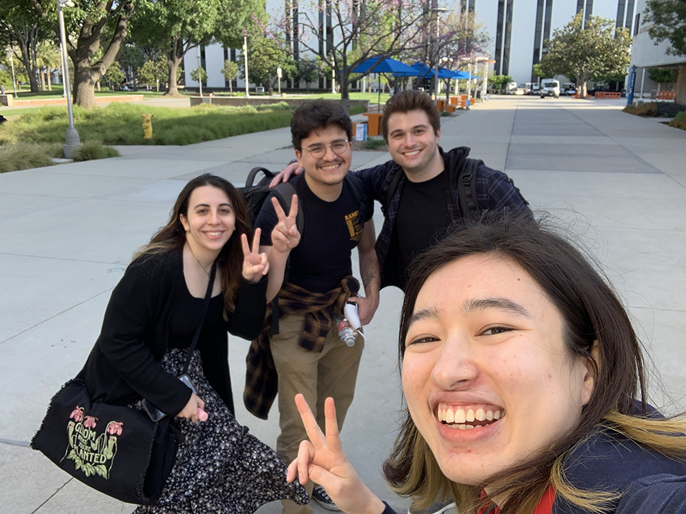 A group of four students posing for a picture with peace signs. 