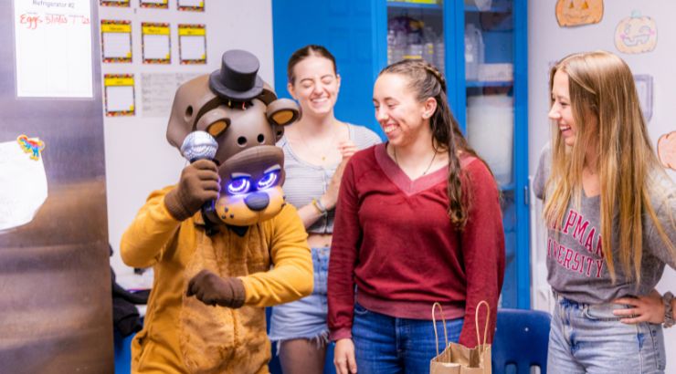 Three Chapman students laughing as the grade-schooler dances in his custom-made Halloween costume. 