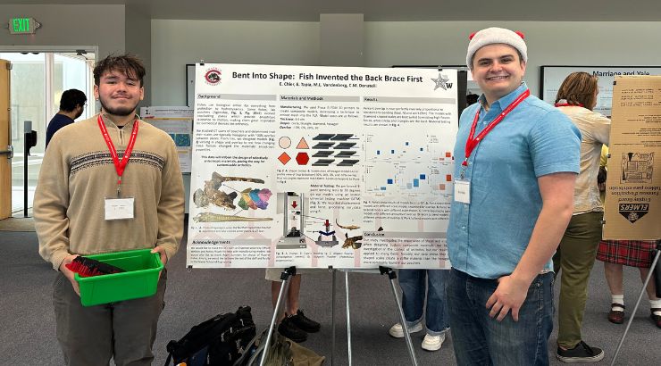 Two Male engineering students standing in front of their research poster.