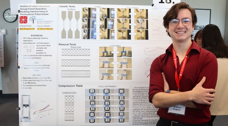 Male Electrical Engineering student standing in front of their research poster.