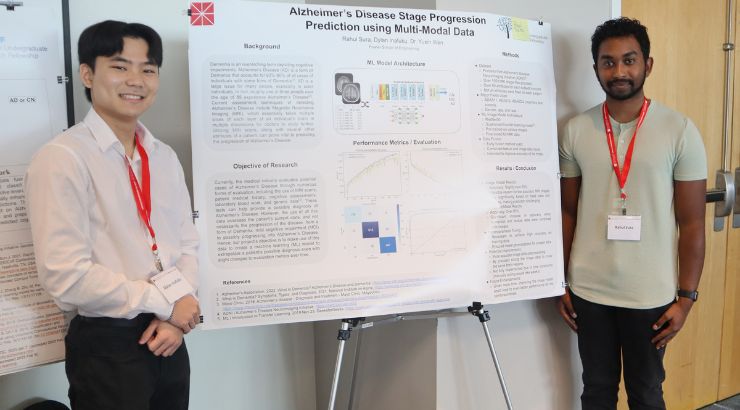 Two Male engineering students standing in front of their research poster.