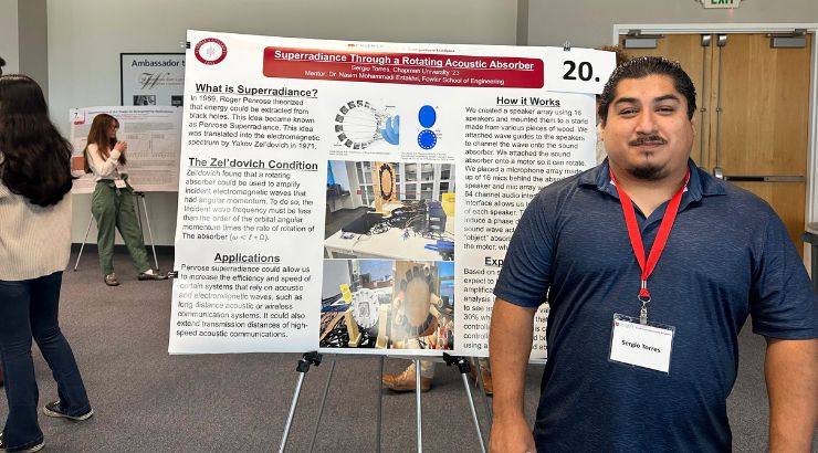 A male engineering students standing in front of their research poster.