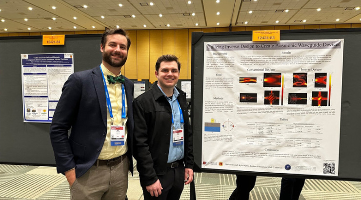 Faculty member, Dr. Harrison, is standing next to his undergraduate student researcher. They are presenting their research at a conference. 