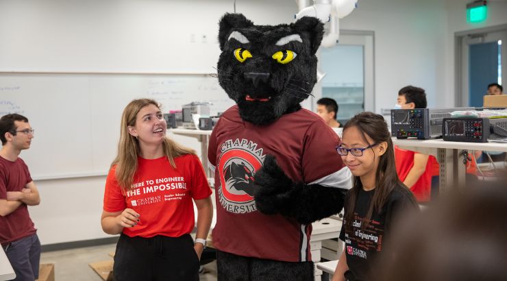 Two students standing next to Chapman University's mascot, Pete the Panther. 