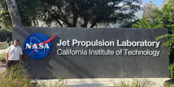 Fares Alhezaimi is standing in front of the NASA JPL sign.