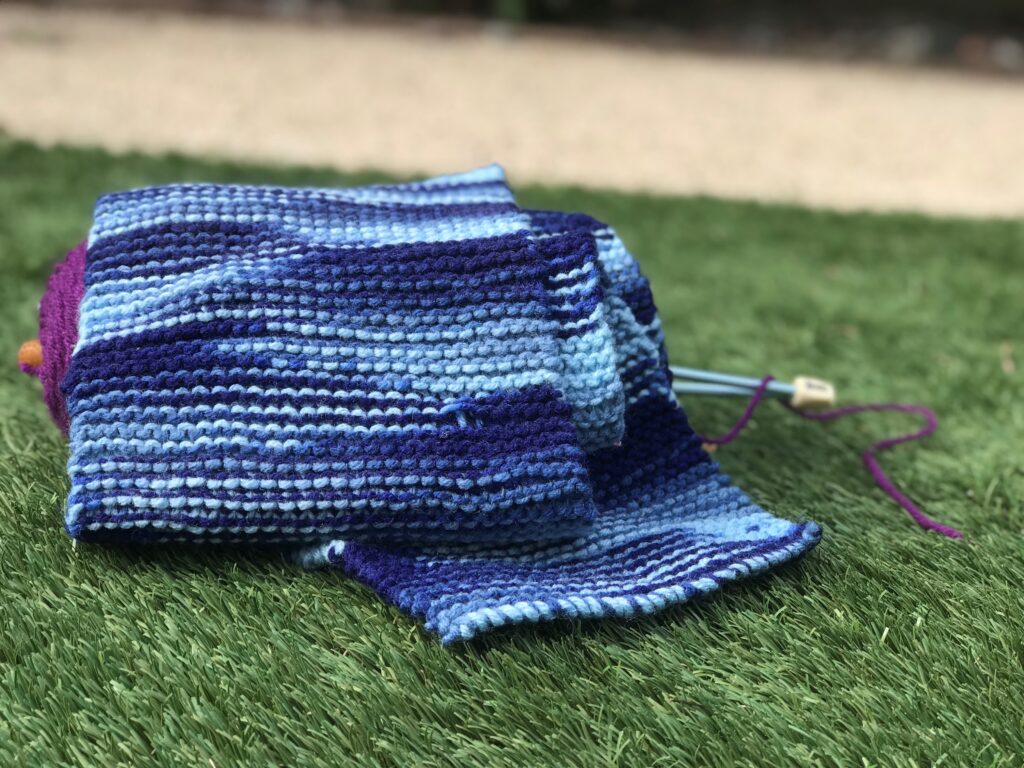 knitted scarf over yarn and knitting needles