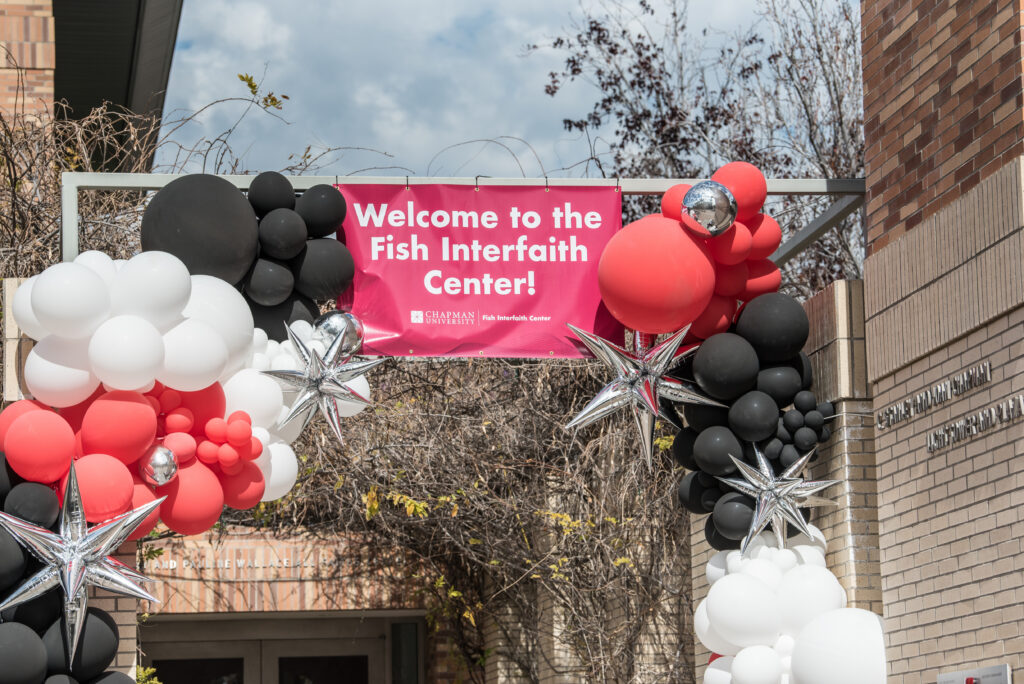Banner that says Welcome to the Fish Interfaith Center surrounded by black red and white balloons