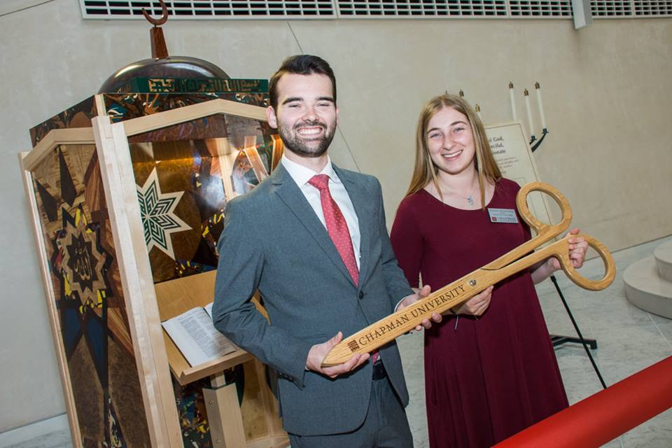 Two student workers holding giant scissors