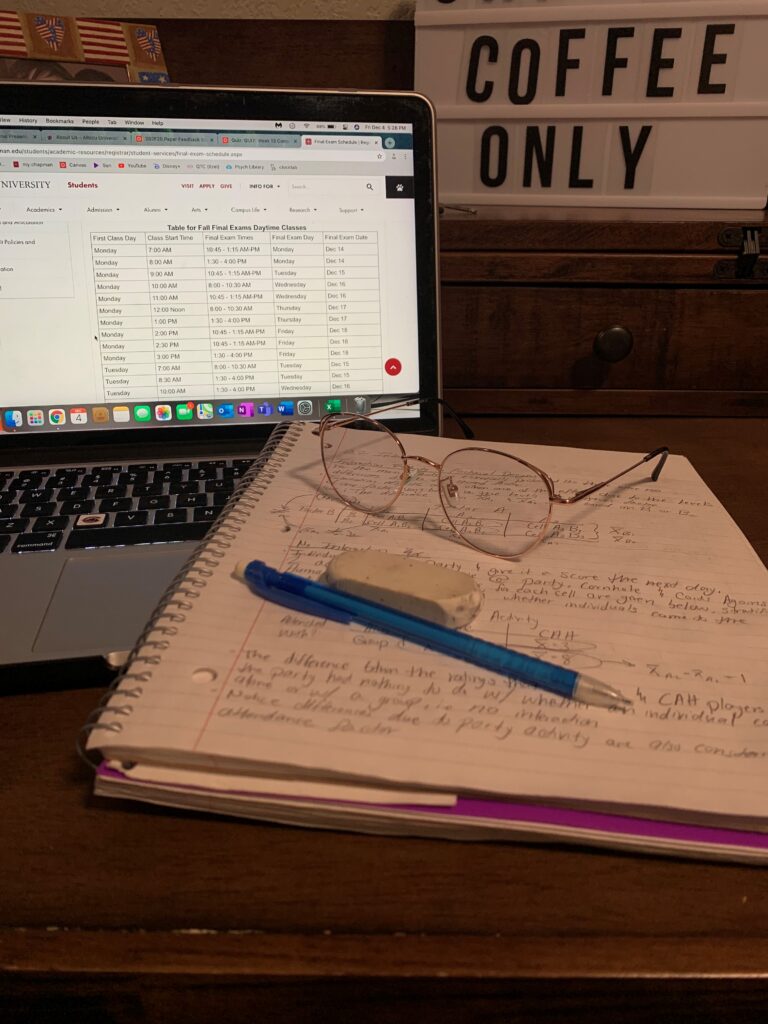 notebook with glasses and a pen in front of a laptop