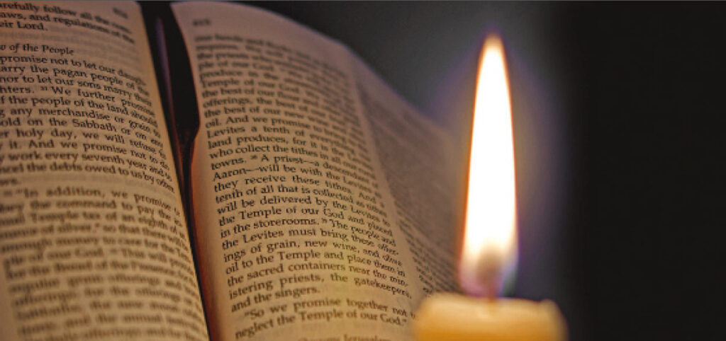 a candle illuminates the pages of the Bibl