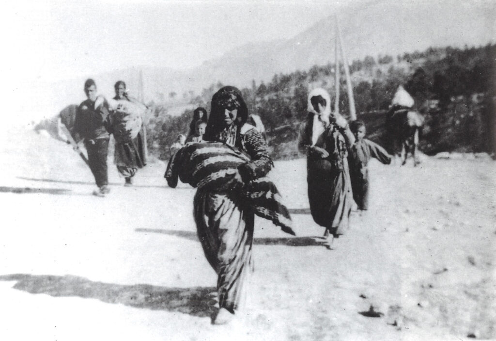 Photo of a woman carrying a bundled child while marching during the Armenian genocide in the Ottoman Empire
