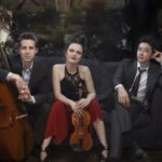 Promotional photo of Ross Gasworth with cello, Iryna Krechkovsky with violin and Kevin Kwan Loucks. Group photo of Trio Celeste.