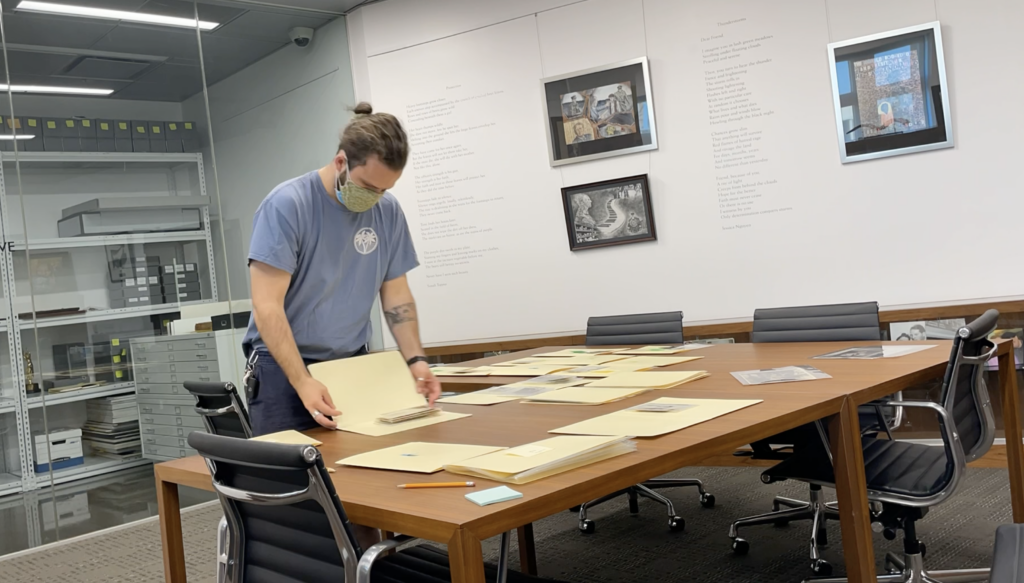 Will Hoskin in processing photographs; image of a student placing a black and white photo in an archival folder