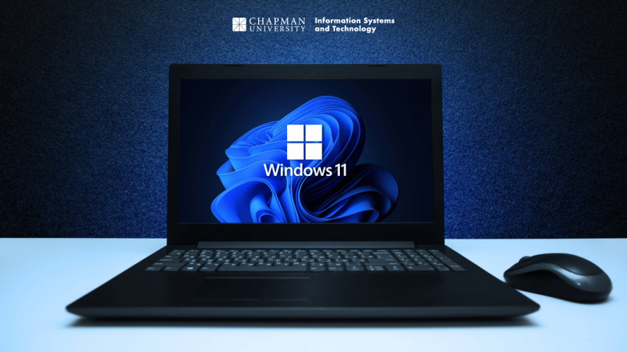 A black laptop on a white surface displays the Windows 11 startup screen, featuring the Windows logo and a swirling blue abstract background. To the right of the laptop is a wireless mouse. The background is a dark blue textured wall with the Chapman University logo and the text “Information Systems and Technology” displayed above the laptop.