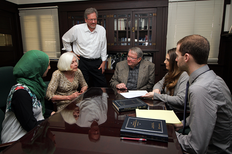 Law students with elder couple at table in the Elder Law offices