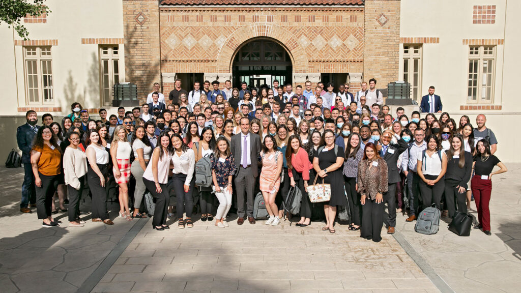 A large group of law students posing in front of a law building with arched doorways