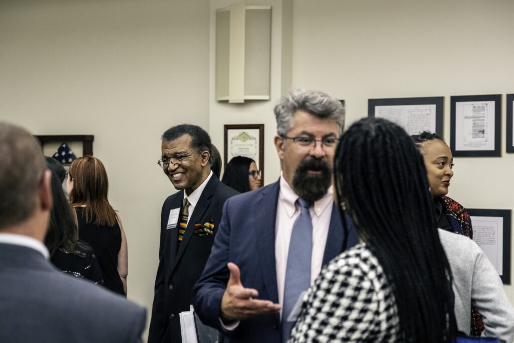 Photograph of Dean Paul Paton (forground) in discussion with Honieh Udenka, Esq., with Justice Richard T. Fields in background